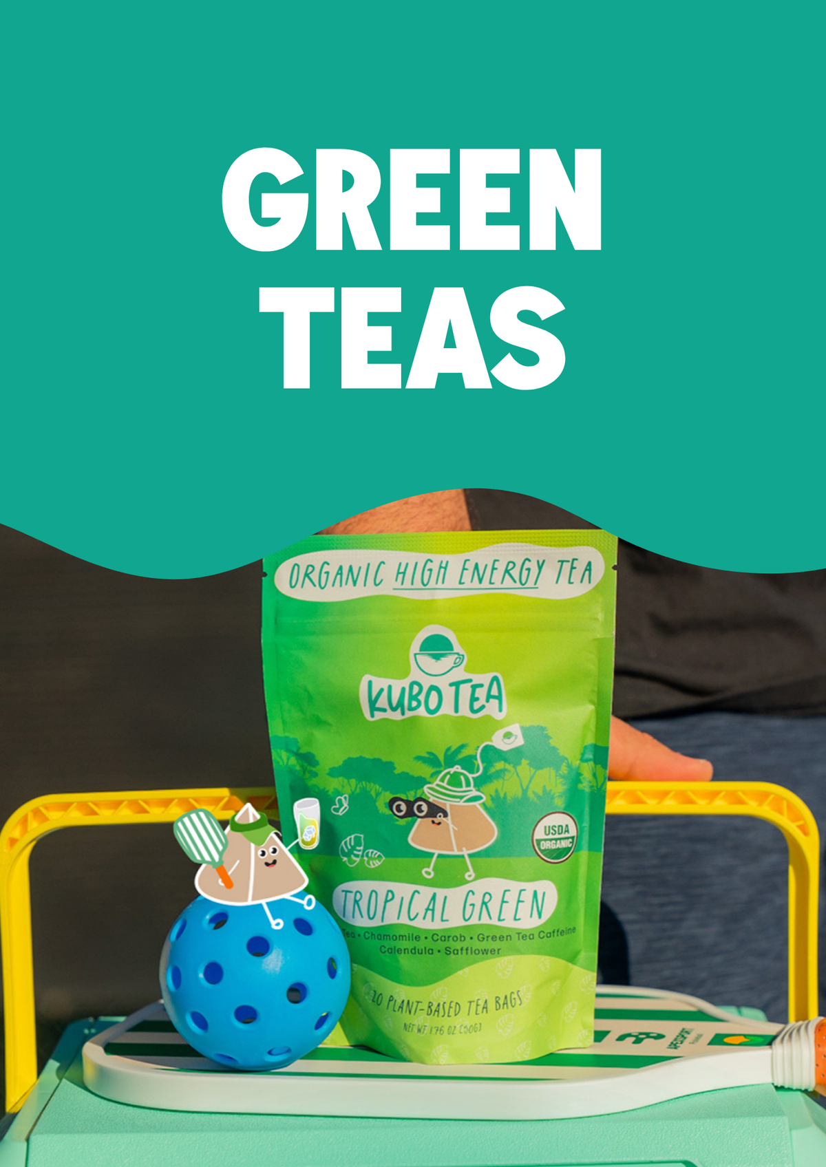 A pouch of Kubo Tea Tropical Green organic high energy tea is displayed on a colorful play structure with a blue ball toy. A large teal graphic overlay at the top reads 'GREEN TEAS' in bold white text.